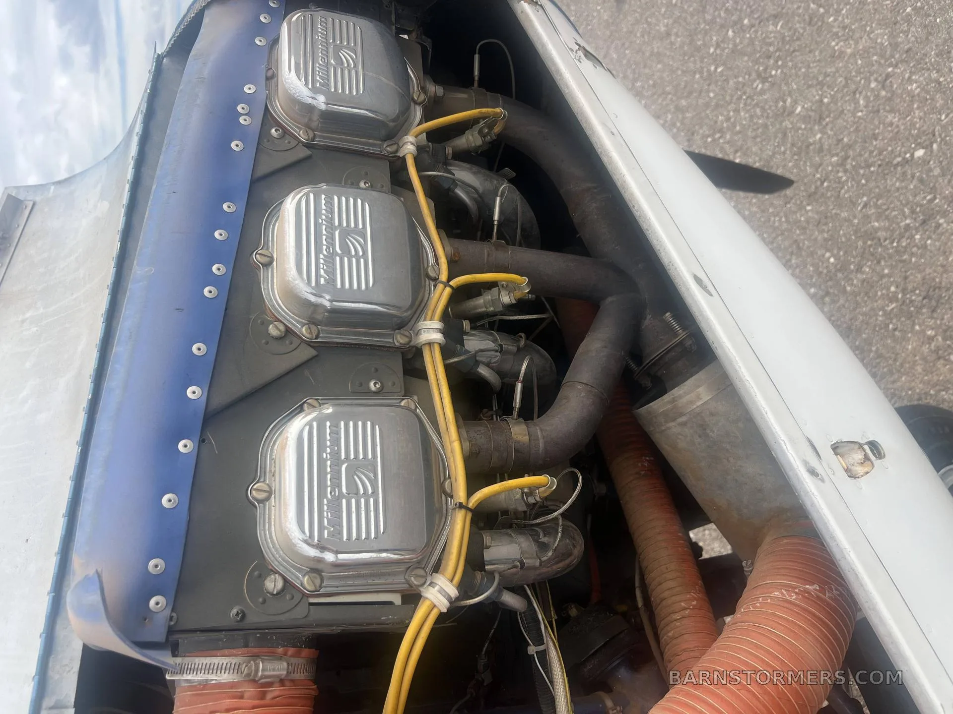 A close-up view of the aircraft's engine, showing three silver cylinder heads with "Continental" branding and yellow ignition wires.