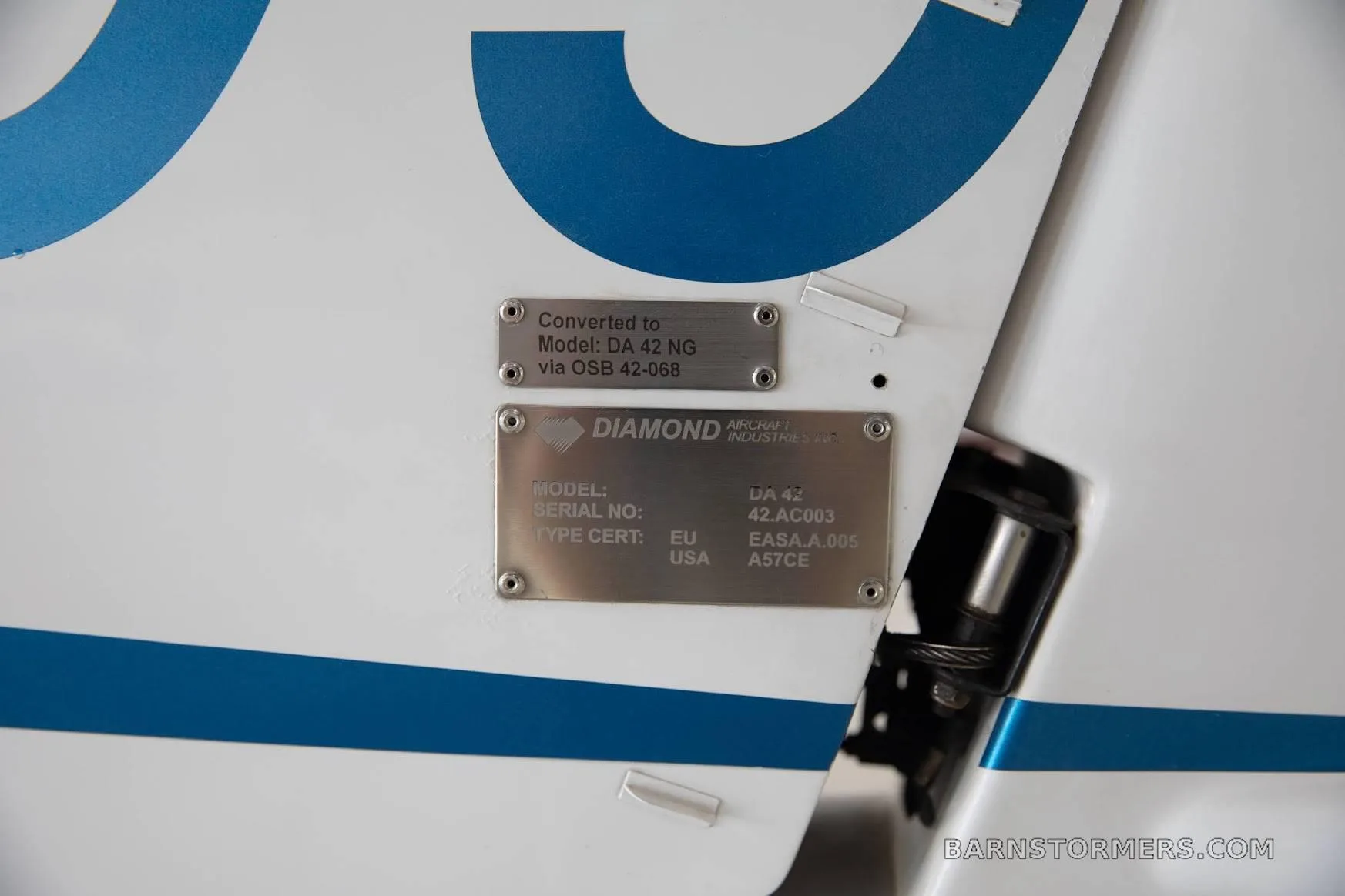Close-up of the data plates on a white Diamond DA42 aircraft, showing model, serial number, and certification details.