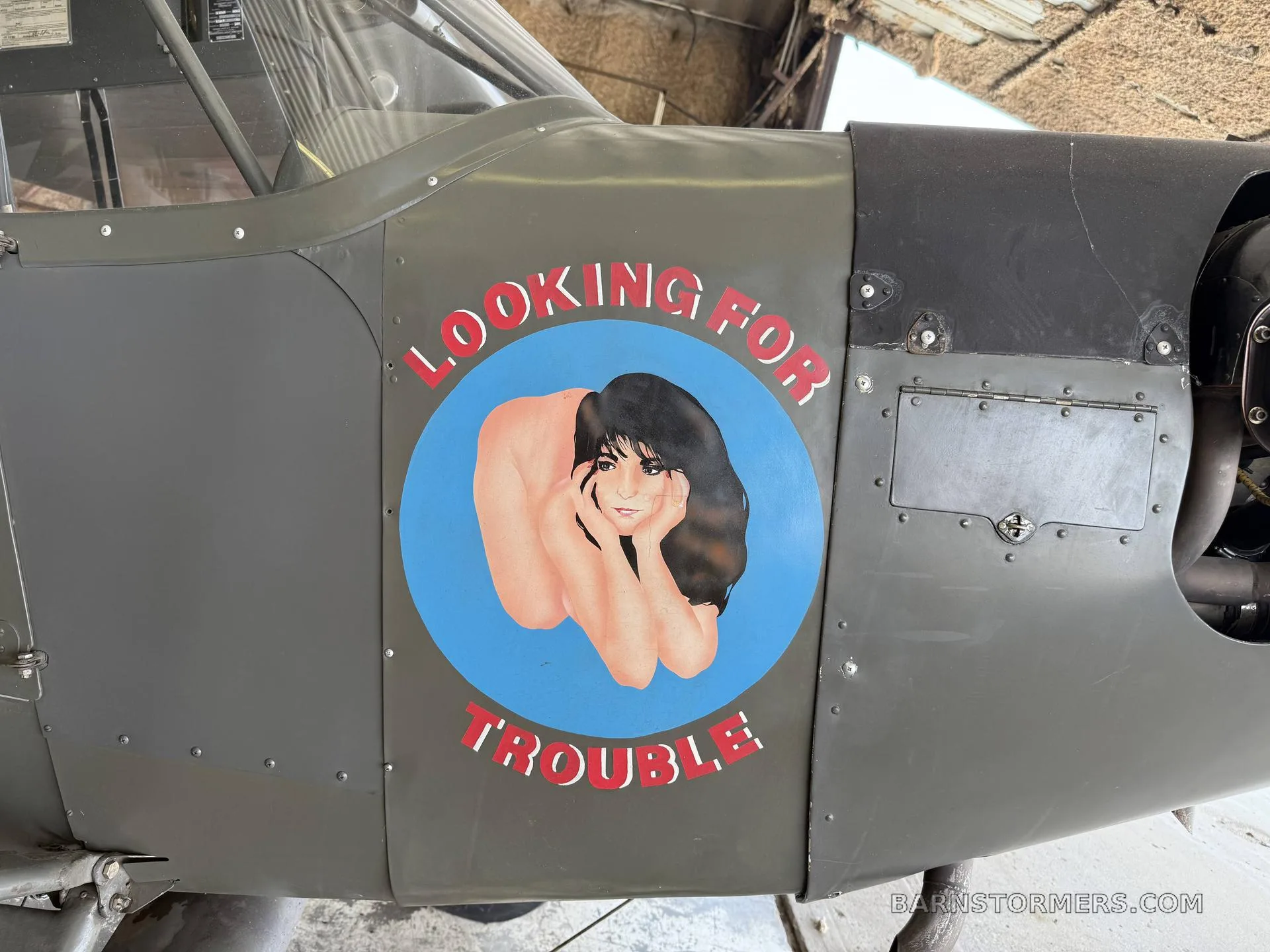 A close-up of the aircraft's fuselage showing "Looking for Trouble" nose art featuring a pin-up girl.
