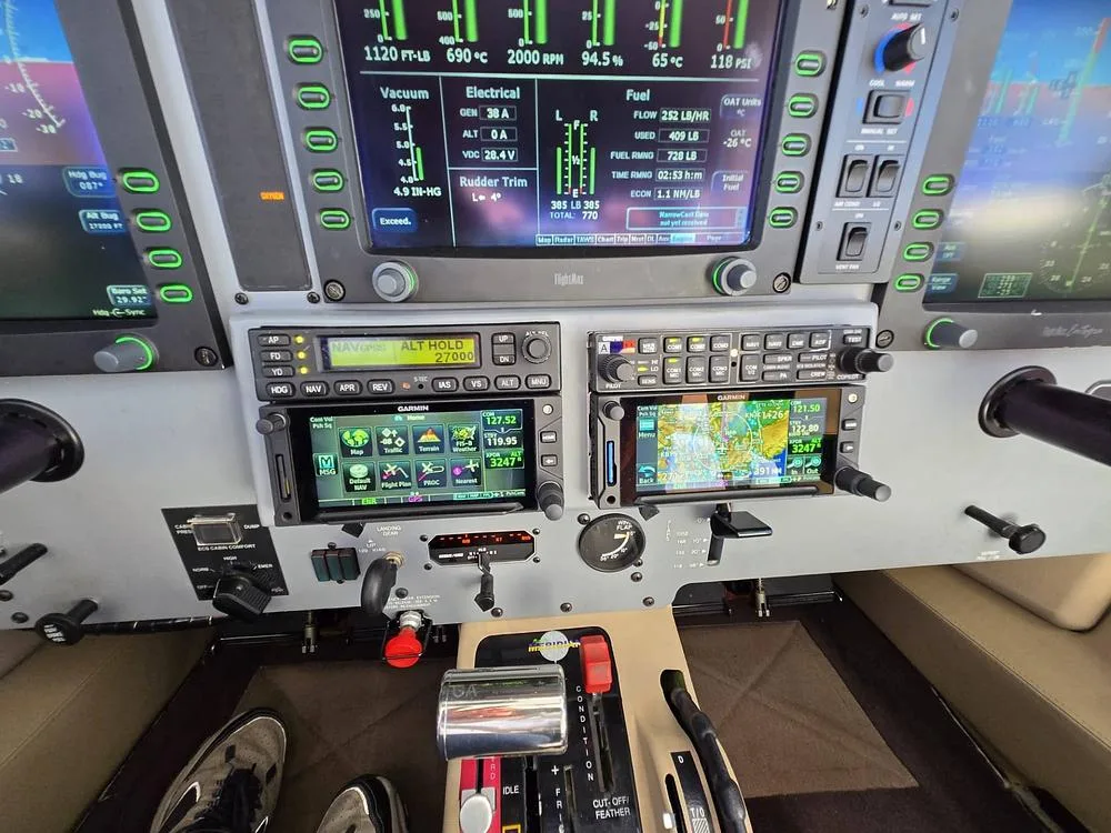 A view of the lower cockpit panel and center console, showing avionics, engine controls, and rudder pedals.