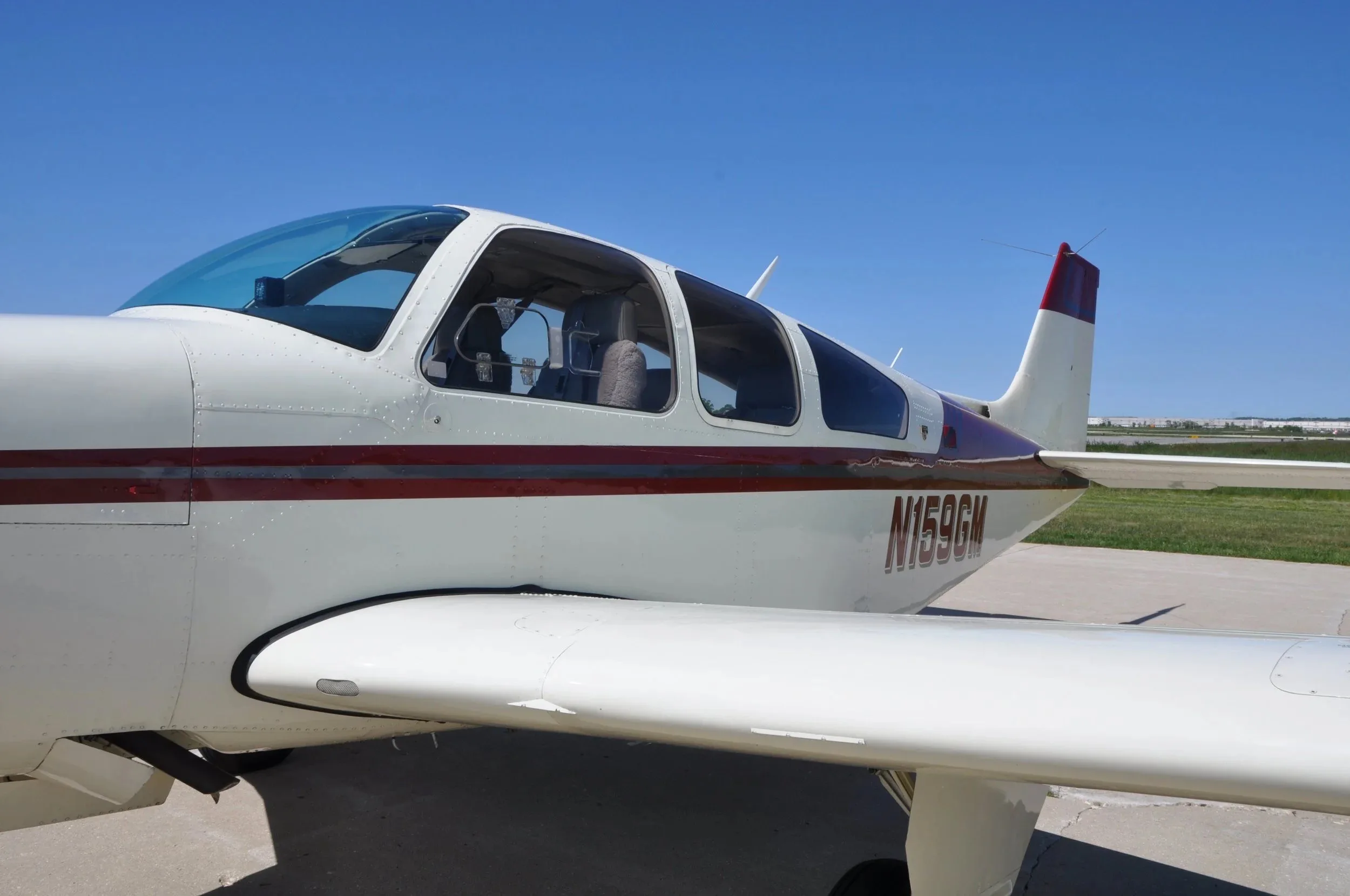 A close-up side view of the cockpit and cabin area of the Beechcraft Bonanza F33A N159GM.