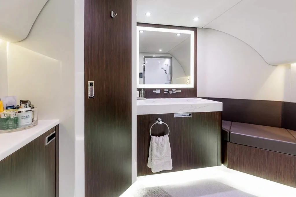A luxurious aircraft lavatory with a modern sink, illuminated mirror, and a reflection of a shower.