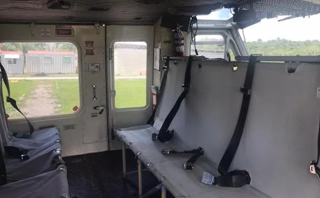 The interior cabin of a helicopter showing utility seating and a fire extinguisher mounted near the door.