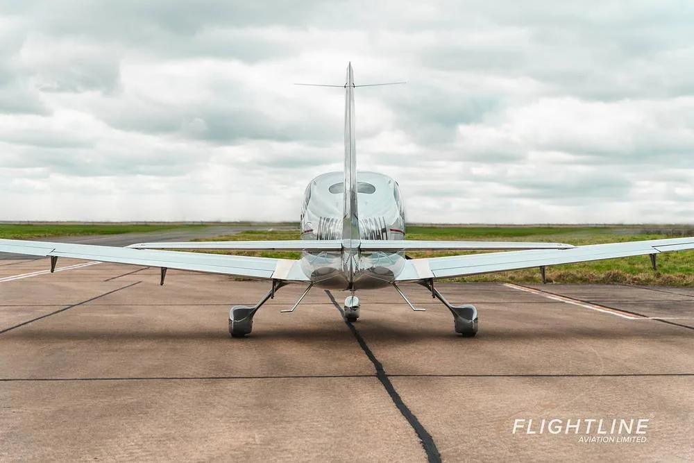A direct rear view of the white Cirrus SR22 aircraft N56AH on a tarmac.