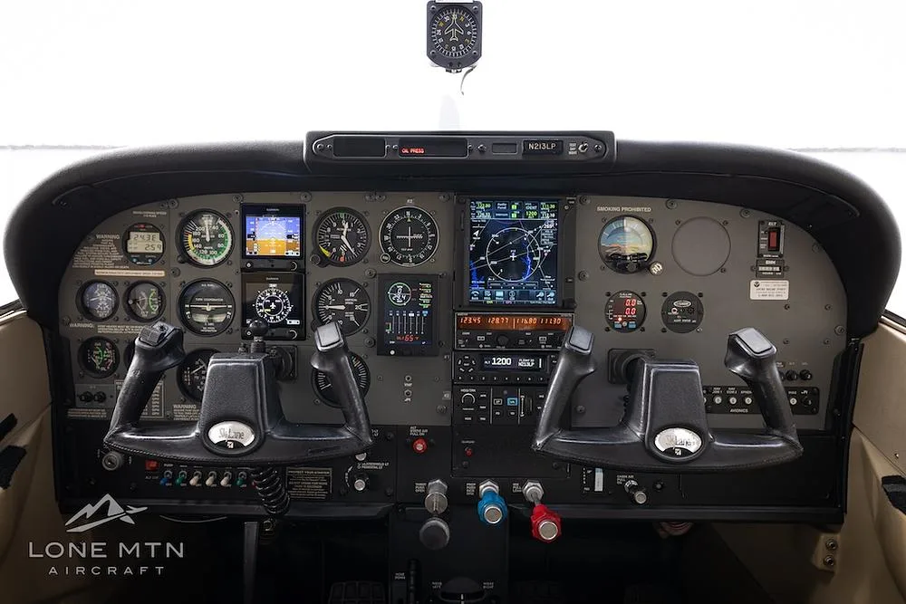 The cockpit of a Cessna 182 Skylane, featuring a mix of analog gauges and modern digital displays, with dual yokes.