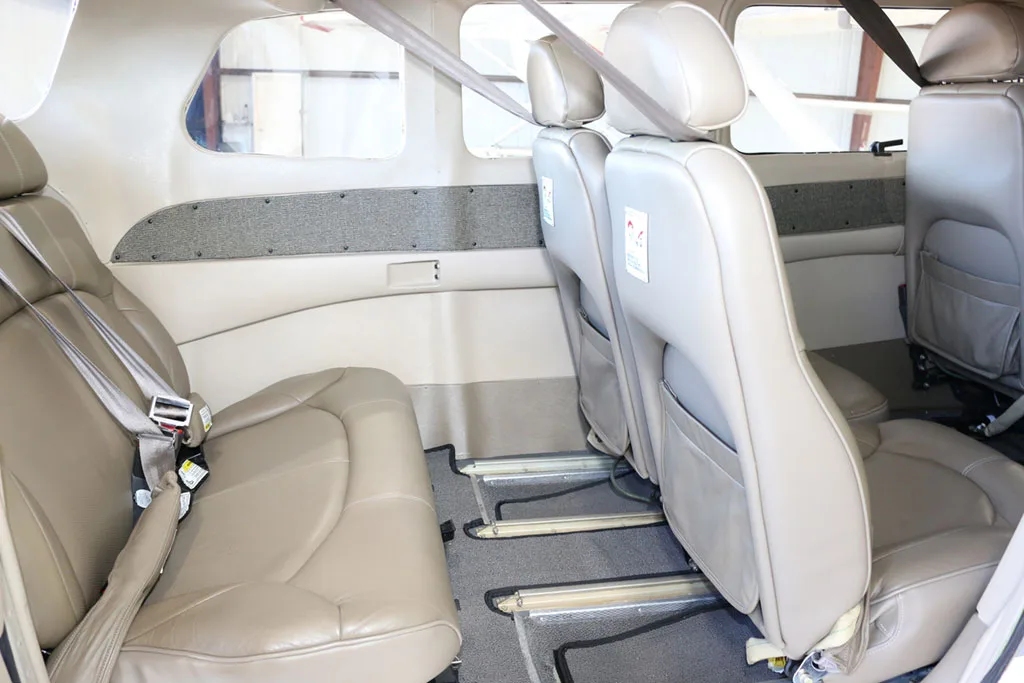 The beige leather interior cabin of the Cessna Stationair TC aircraft, showing passenger seats.