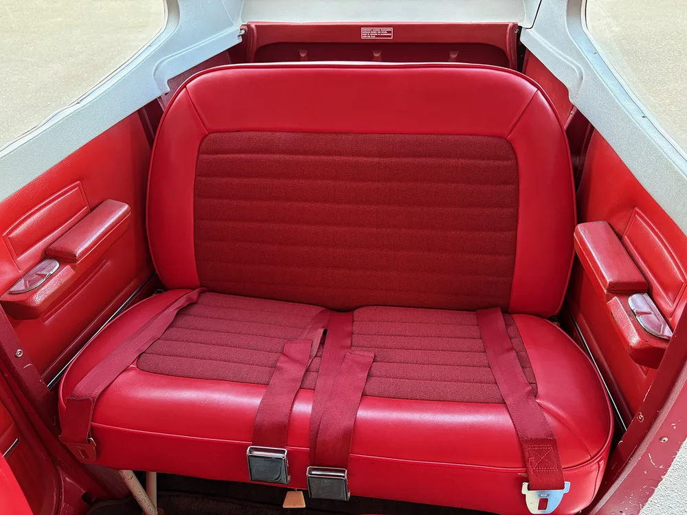 A close-up view of the red rear bench seat in the aircraft's cabin.
