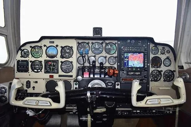 The cockpit instrument panel of a general aviation aircraft, featuring analog gauges and a modern GPS display.