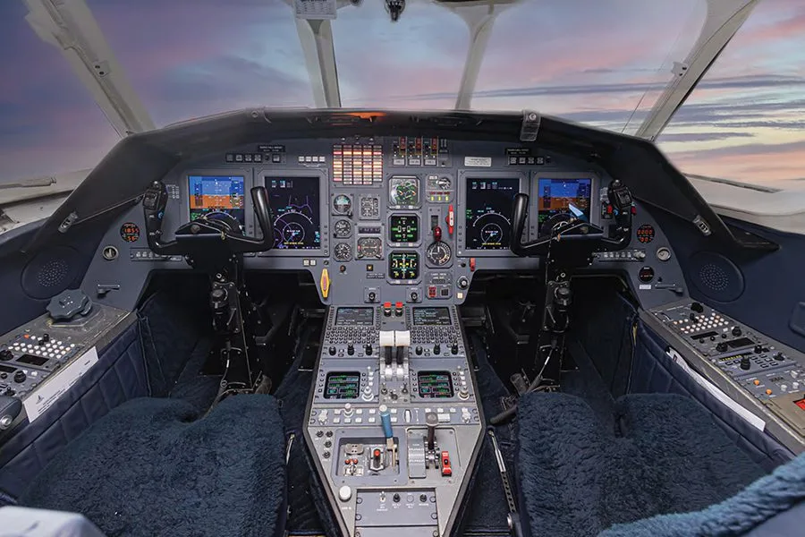 The cockpit of a business jet features multiple digital displays and control panels.