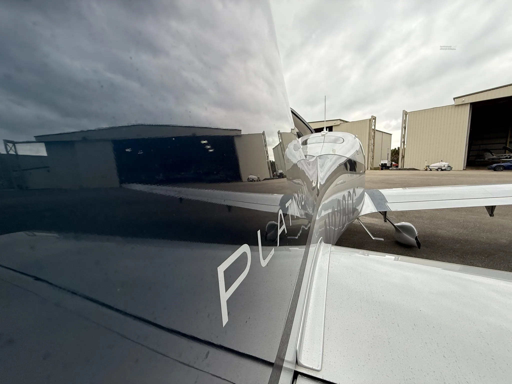 A close-up view of the tail of the N228CC Cirrus SR22T, showing the "PLATINUM" designation and reflections of hangars.