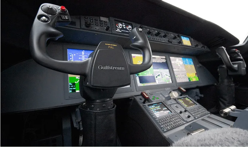 The cockpit of a Gulfstream aircraft, showing the instrument panel with multiple displays and the pilot's yoke.