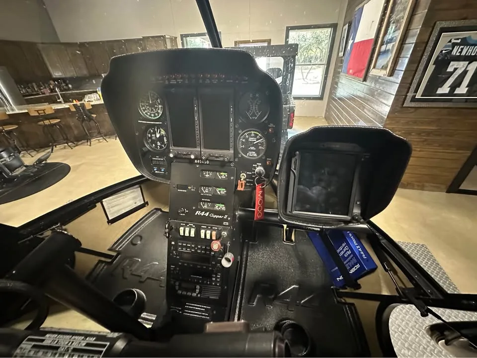 The cockpit of a Robinson R44 helicopter showing the instrument panel and controls.