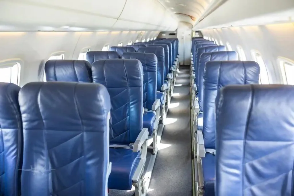Rows of blue passenger seats are visible in the interior cabin of an aircraft.