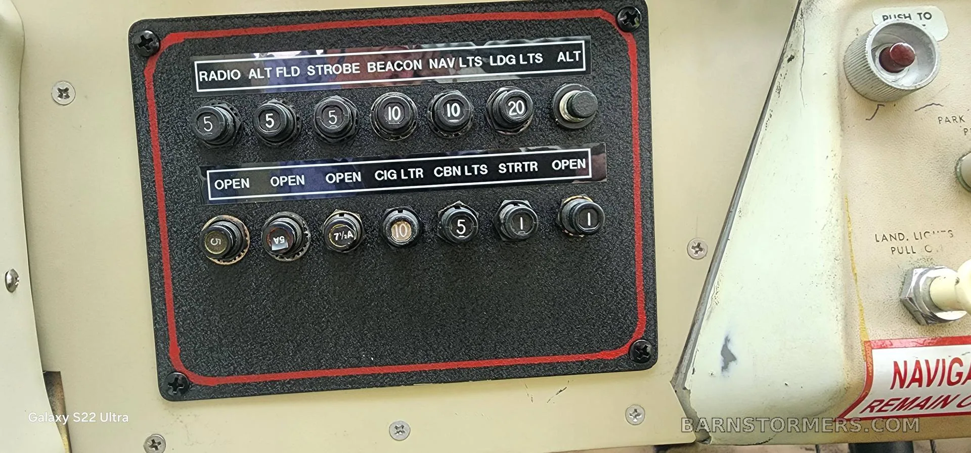A close-up of an aircraft's black switch panel with white labels for lights and other functions.