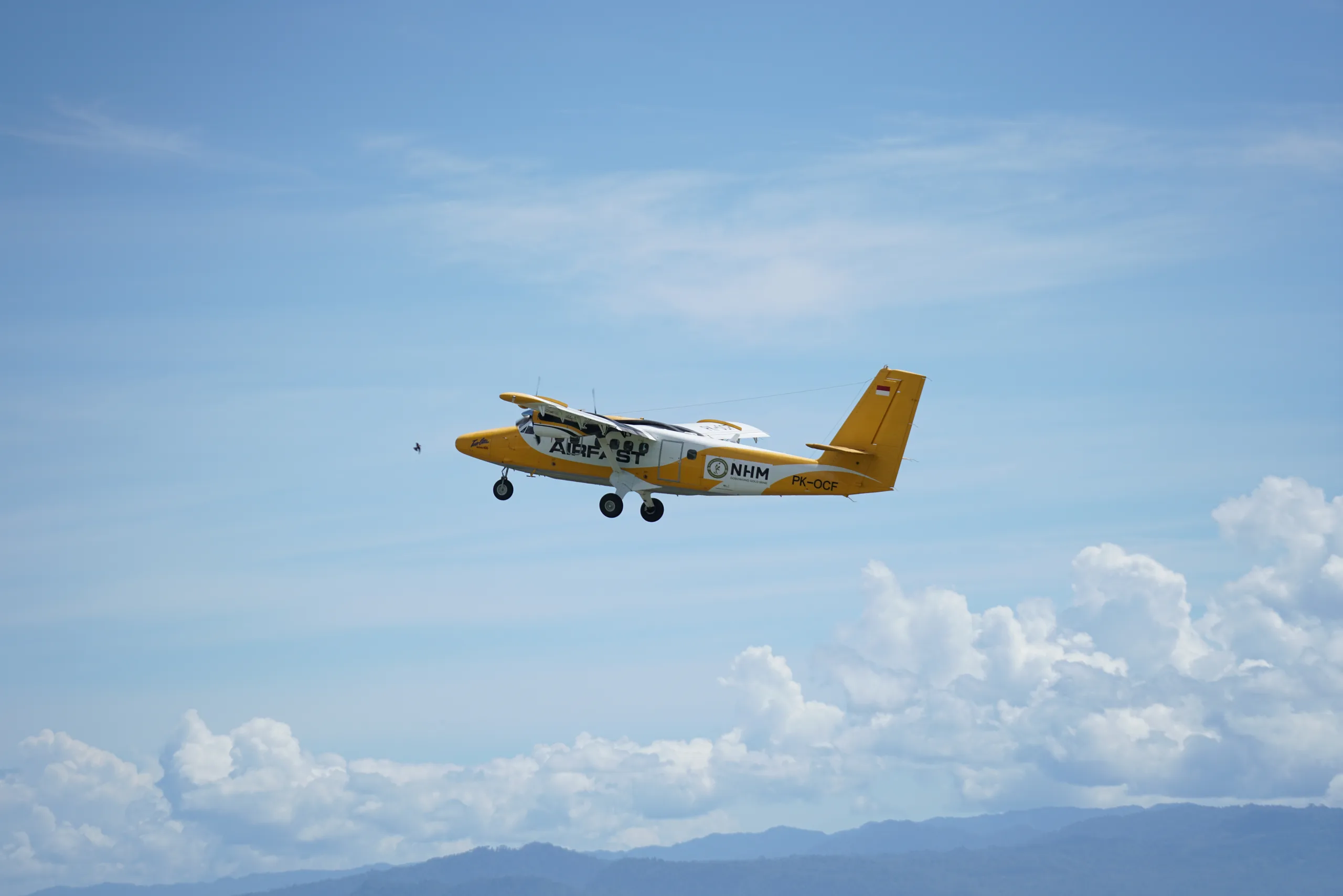 PK-OCF Twin Otter in flight against a cloudy sky.