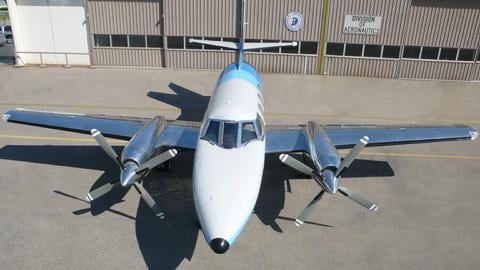 A Beechcraft Baron with a blue and white paint scheme parked on the tarmac.