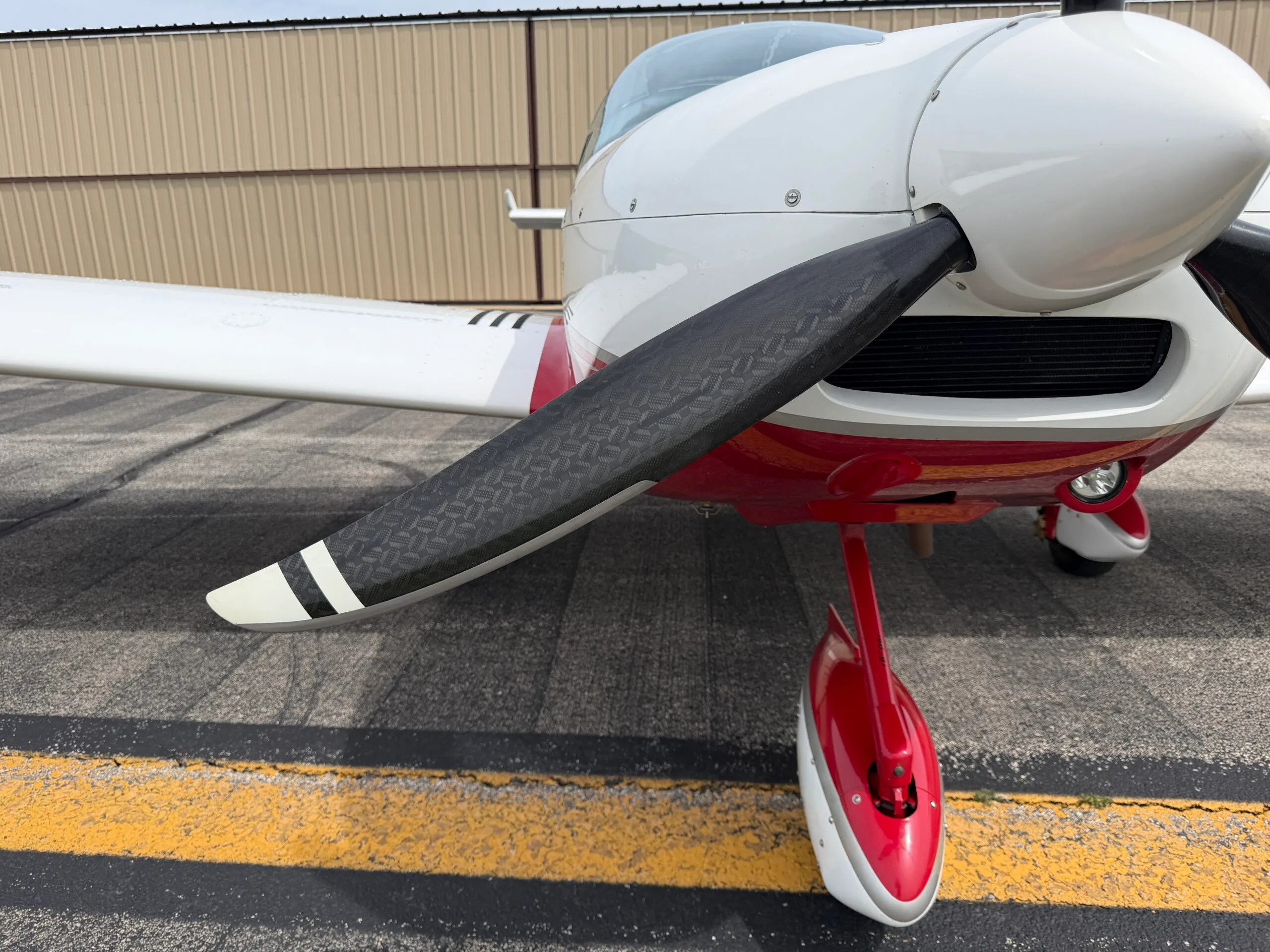 Close-up of the propeller and red and white nose landing gear of the SportCruiser aircraft.
