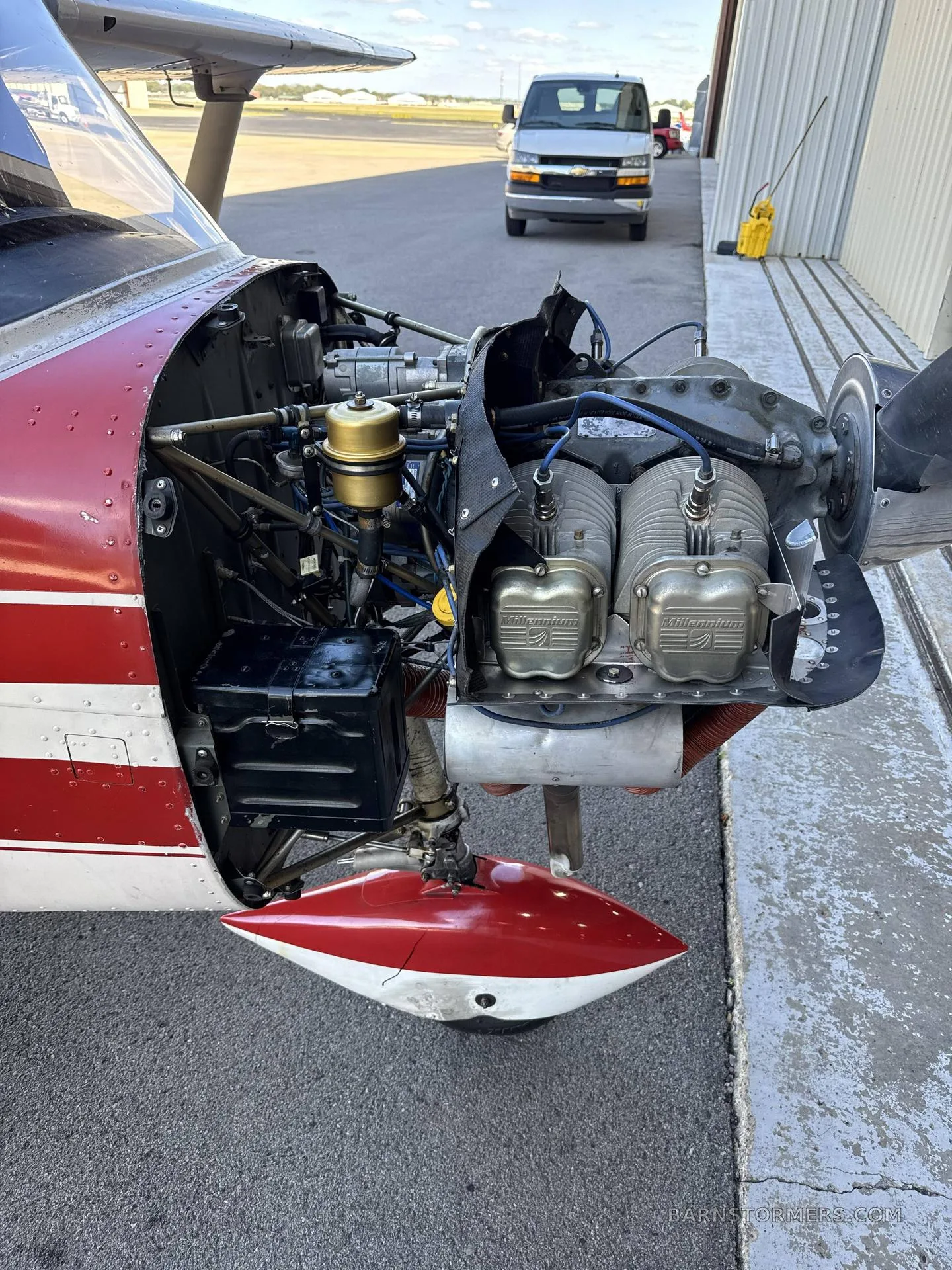 A close-up view of the open engine compartment of a red and white aircraft, showing the engine components.