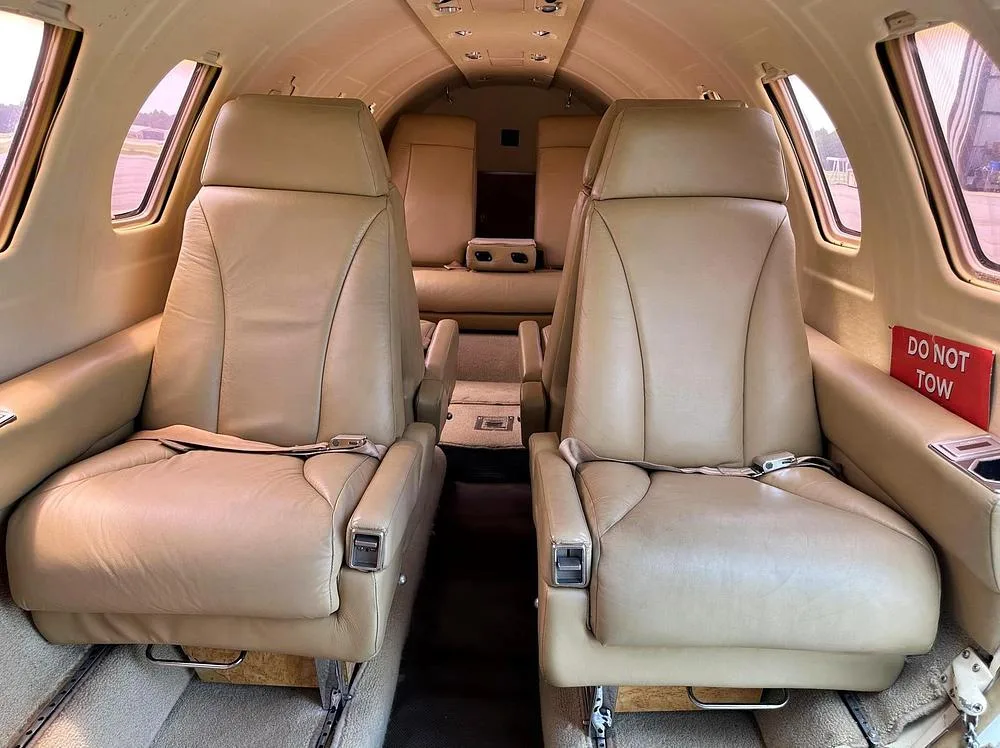The beige leather passenger seats in the cabin of a business jet, facing each other.