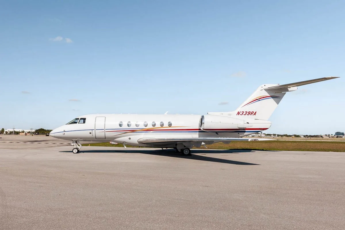 A white Hawker 800XP business jet with red and blue stripes, registration N339RA, parked on the tarmac from a slightly rearward angle.