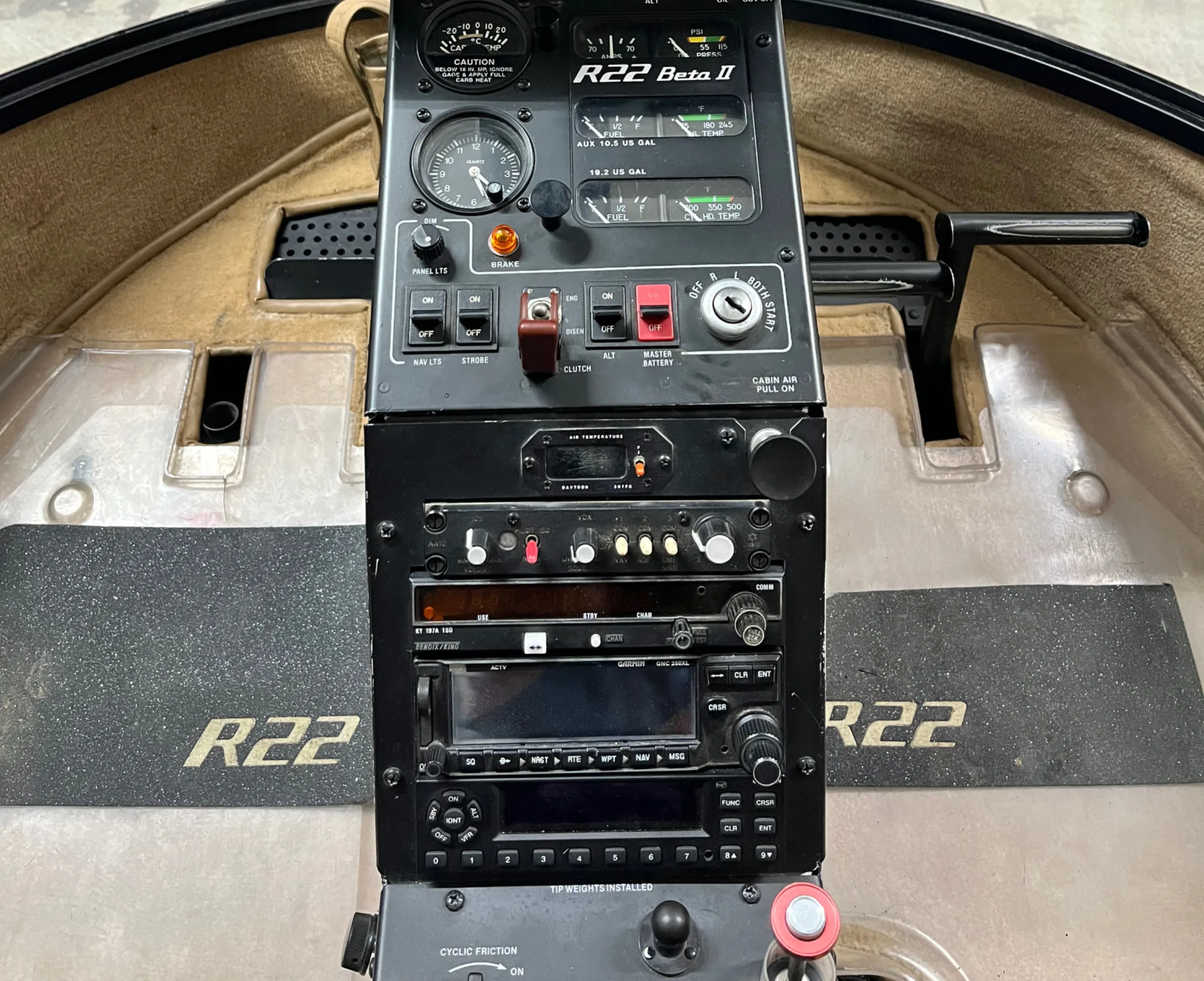 The cockpit instrument panel of a Robinson R22 Beta II helicopter, showing gauges, radios, and controls.