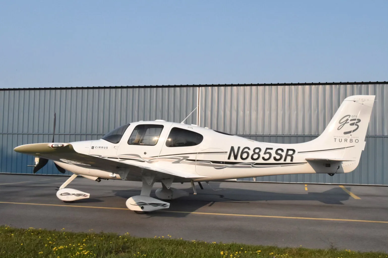 A side view of the white Cirrus SR22T aircraft (N685SR) with black and grey stripe livery.