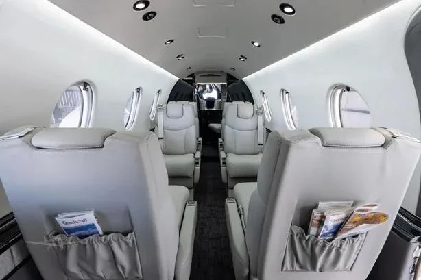 The aircraft cabin interior with light grey leather seats in a club configuration, looking towards the rear.