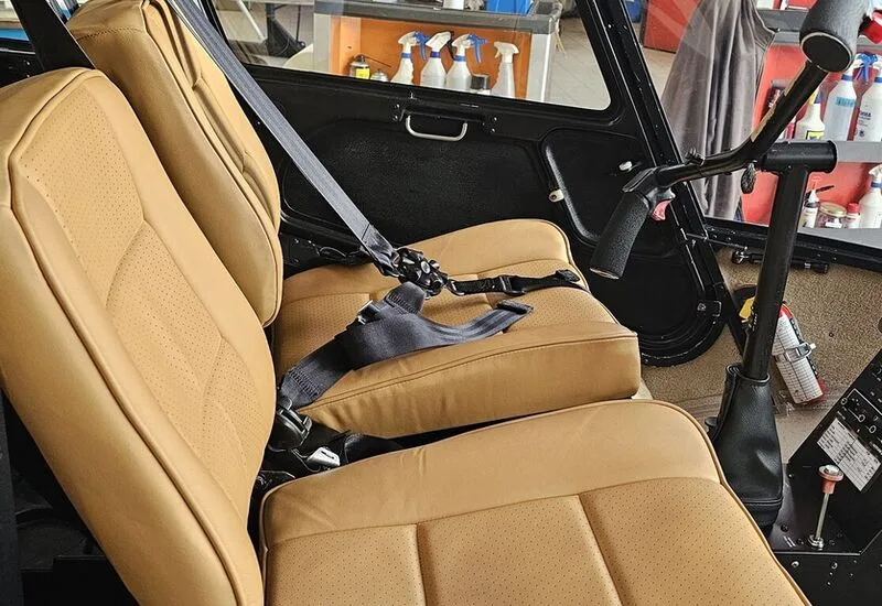 Close-up of the tan leather seats and seatbelts inside the helicopter cabin.