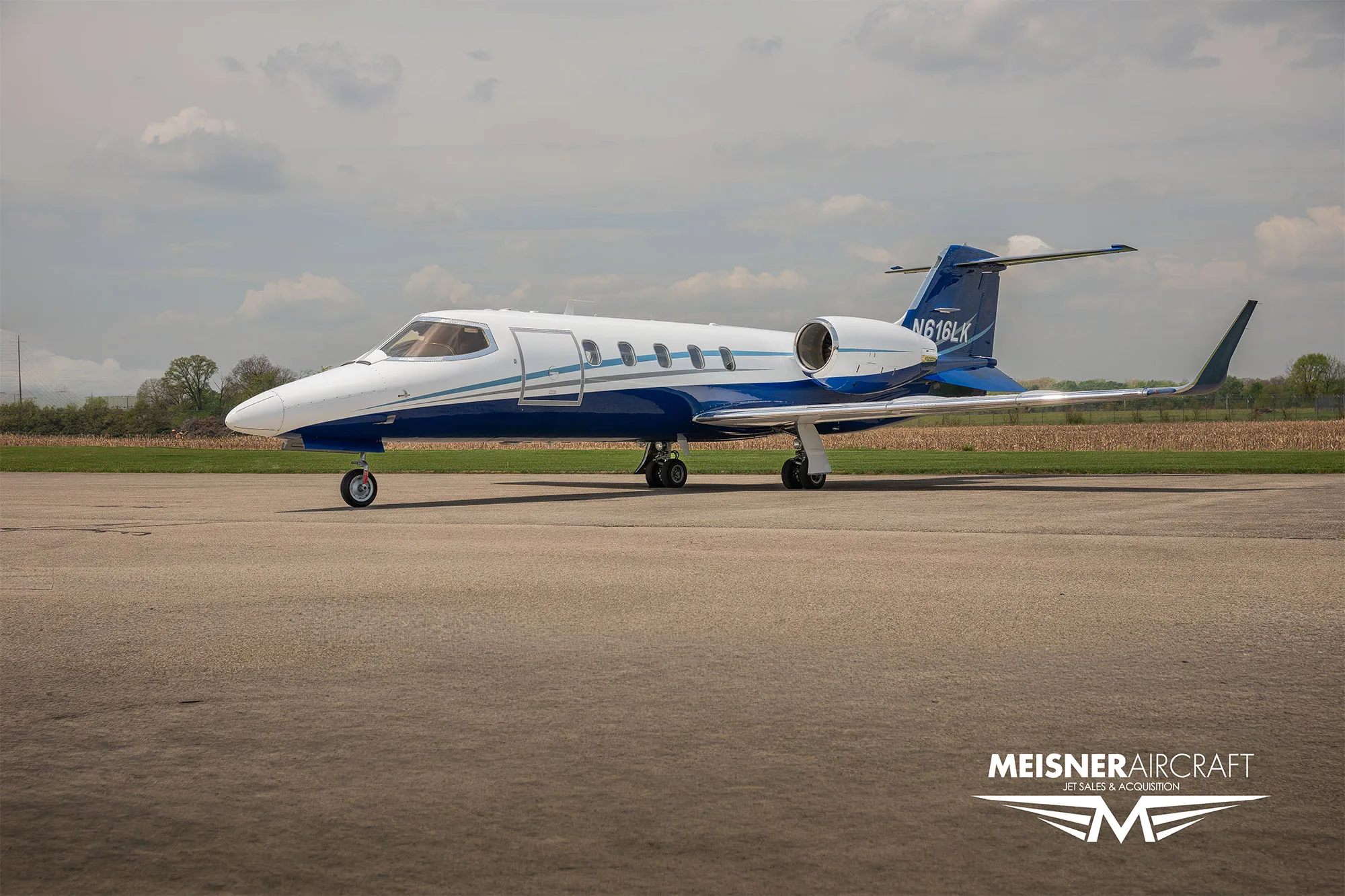 A white and blue Learjet N616LK parked on an airfield with a "Meisner Aircraft" watermark.