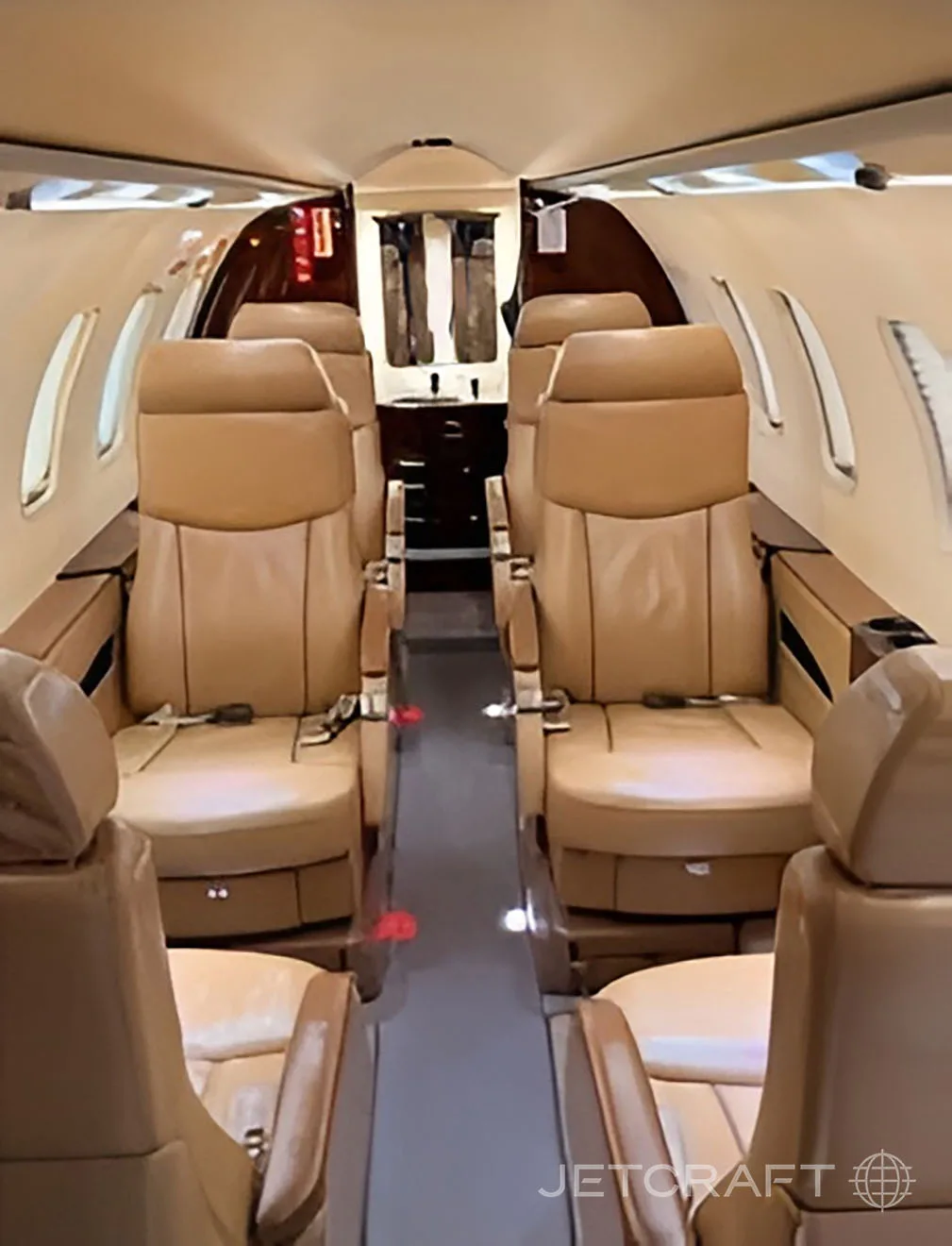 The interior cabin of a business jet with tan leather seats arranged in a club configuration.