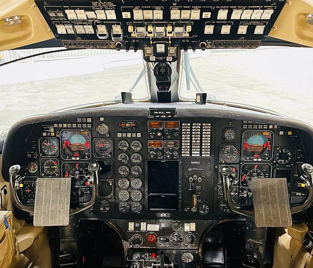 Detailed view of a private jet cockpit with numerous analog gauges, digital displays, and control panels.