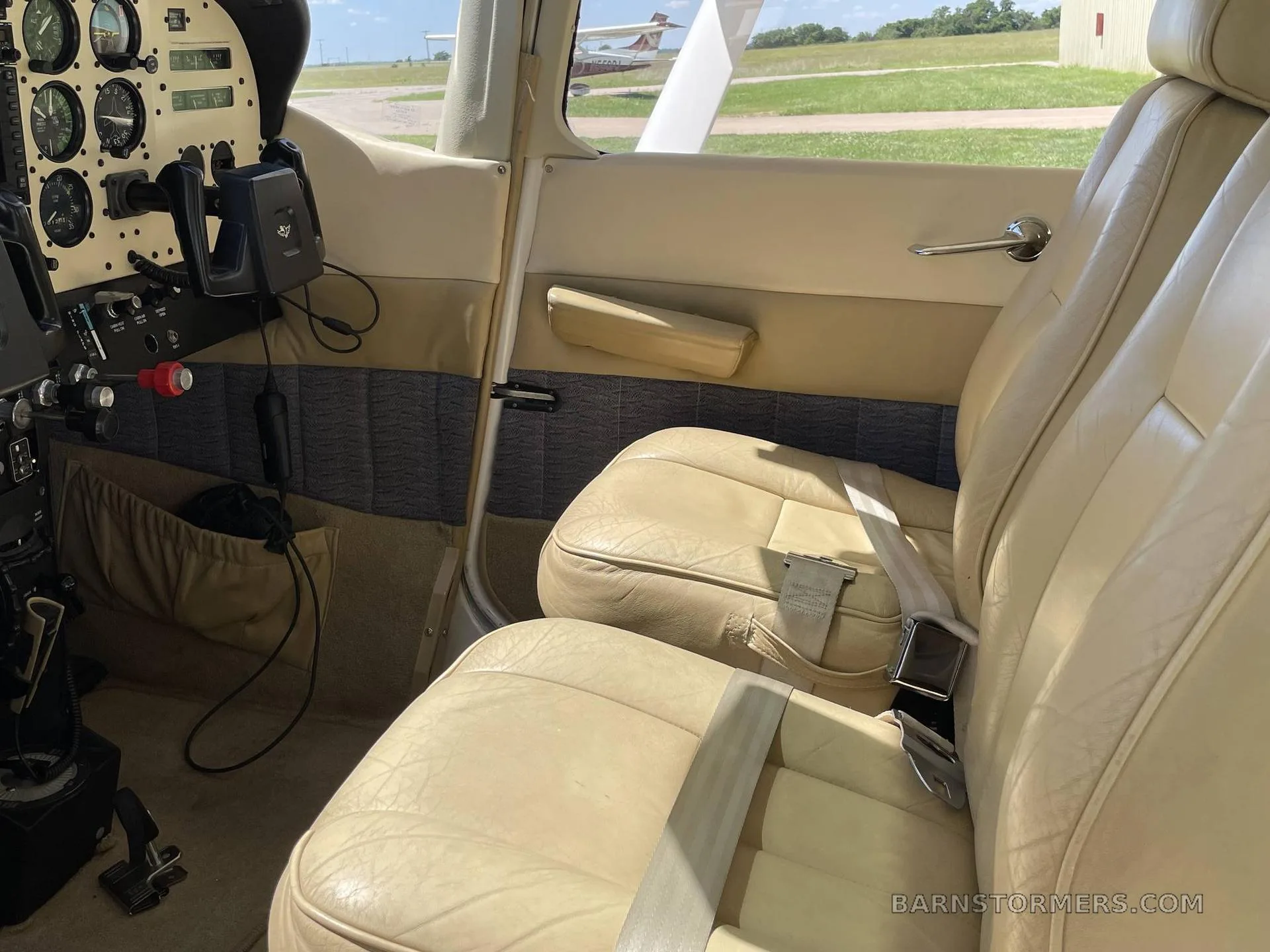 Close-up view of the light tan leather front seats and the left side of the instrument panel in a small aircraft.