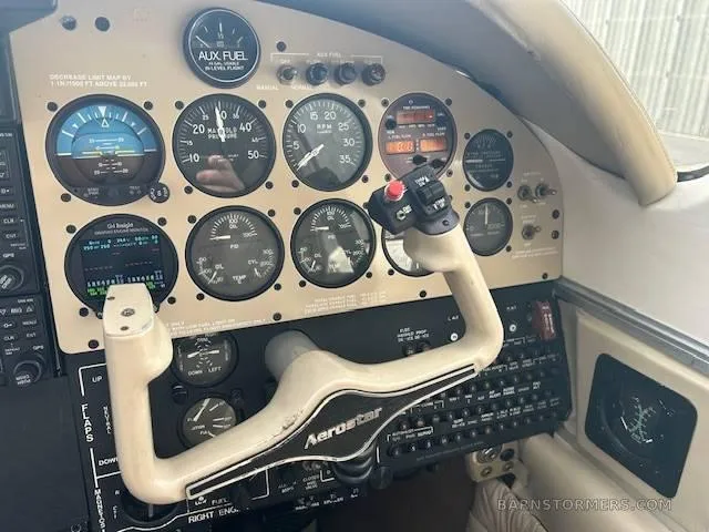Close-up view of the aircraft's instrument panel with analog gauges and a beige "Aerostar" branded yoke.