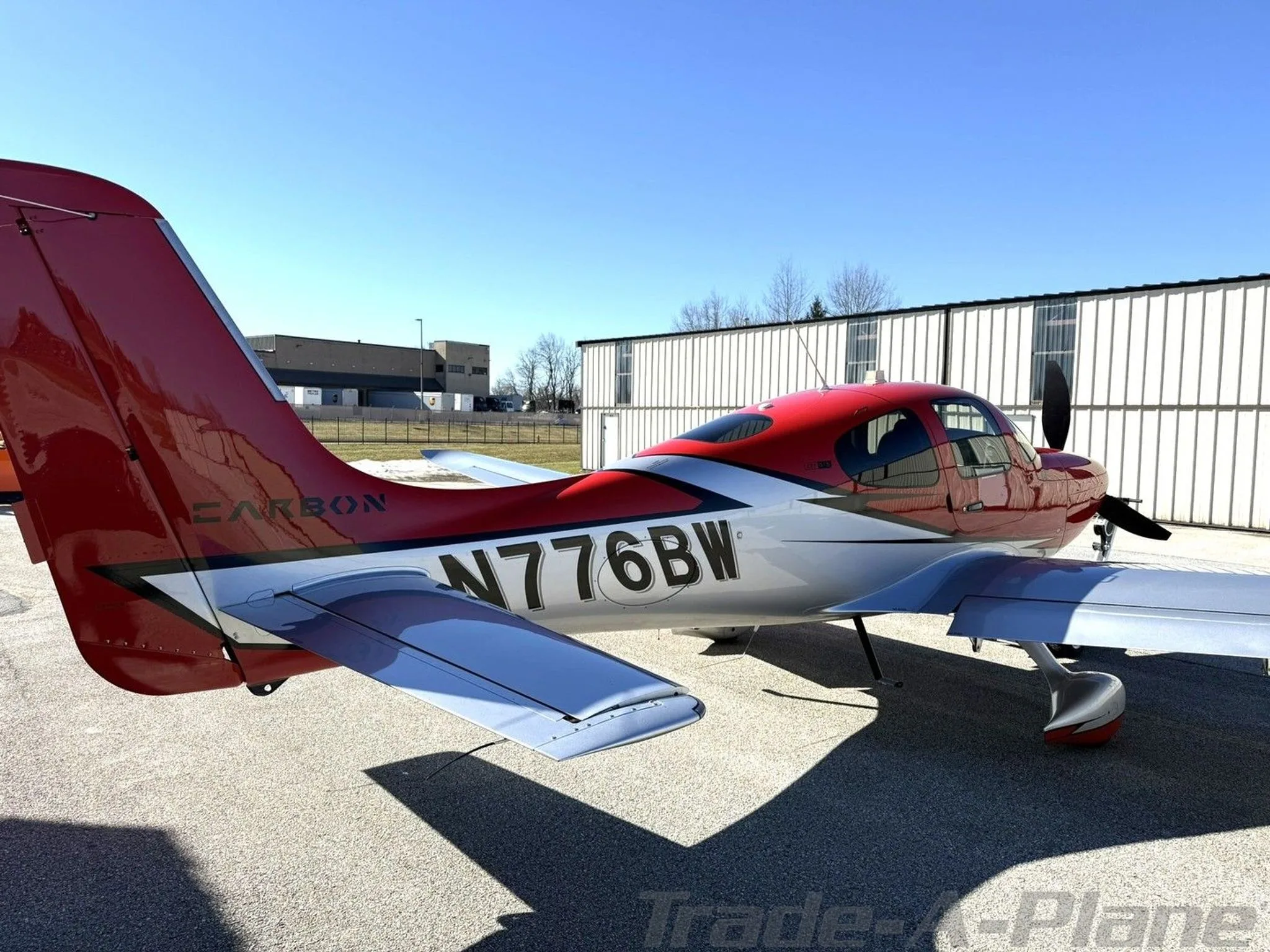 A rear-side view of the red and silver Cirrus SR22T aircraft, N776BW, showing the tail and registration.