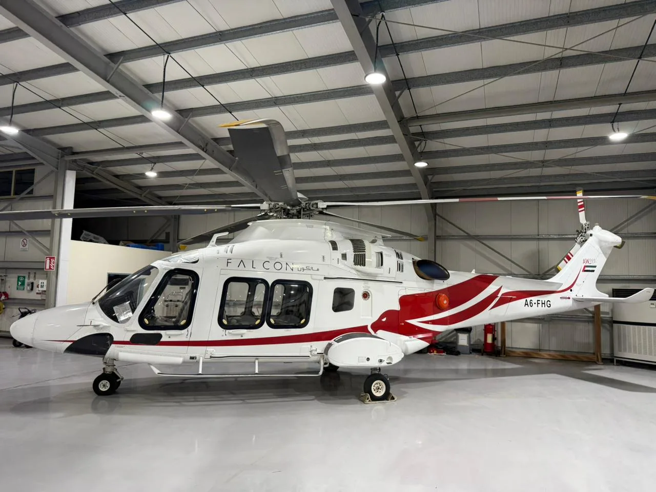 Side view of the A6-FHG helicopter parked in a hangar.