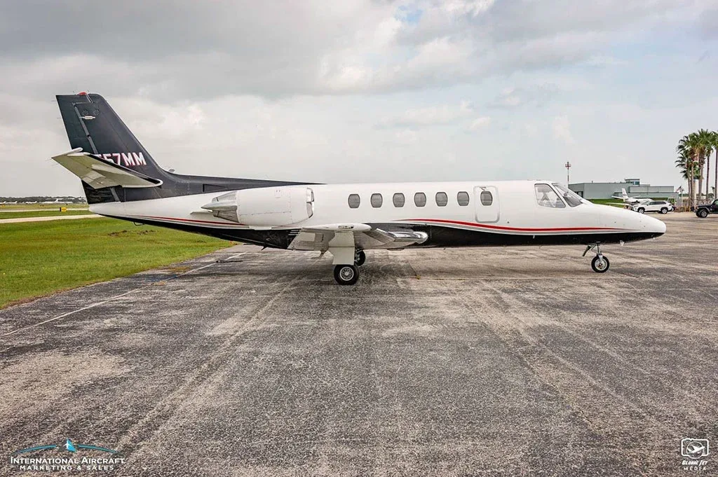 A low-angle side view of a white and black Cessna Citation business jet (N557MM) parked on an airfield.