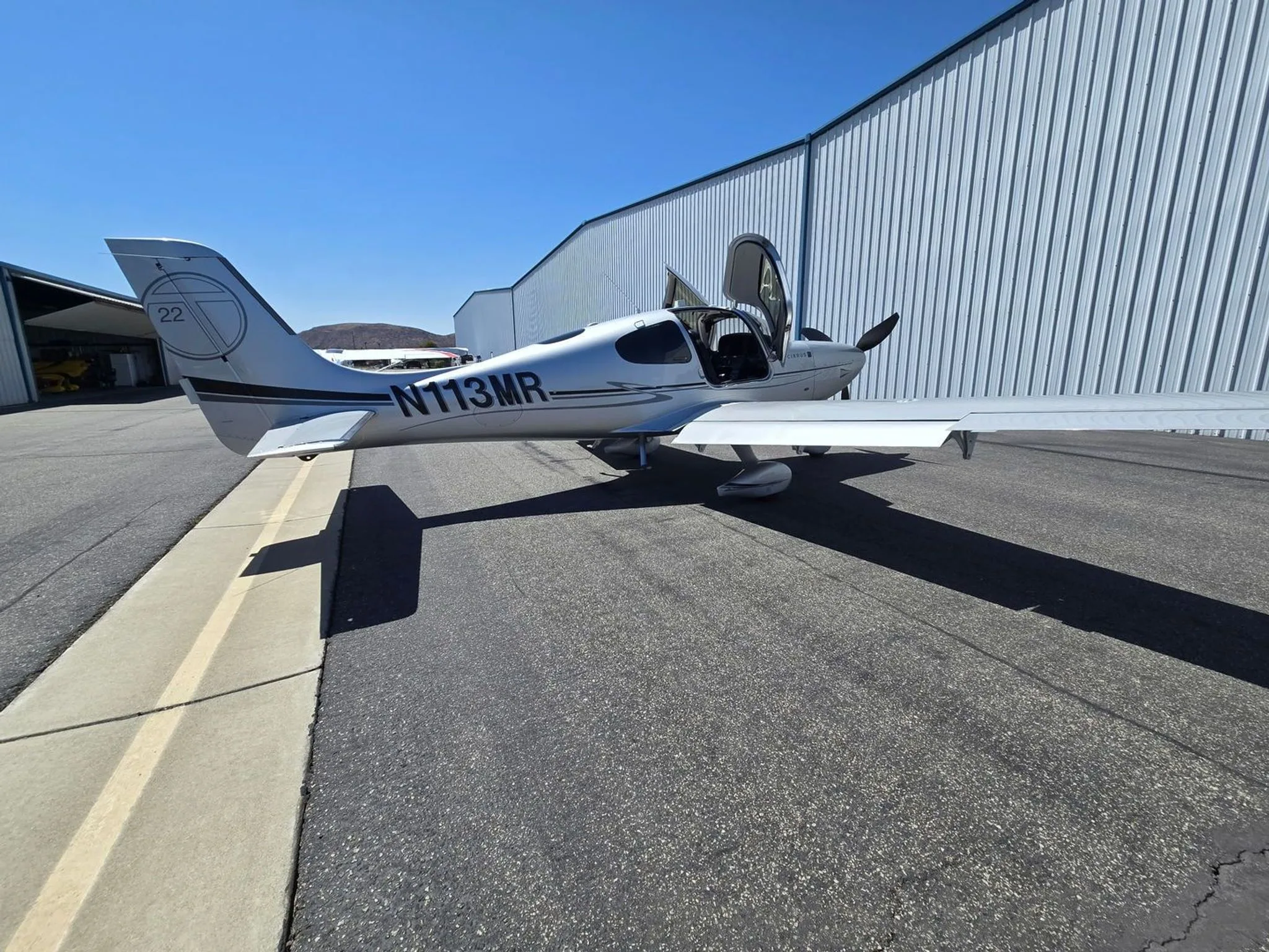 A side view of the aircraft parked at a hangar.
