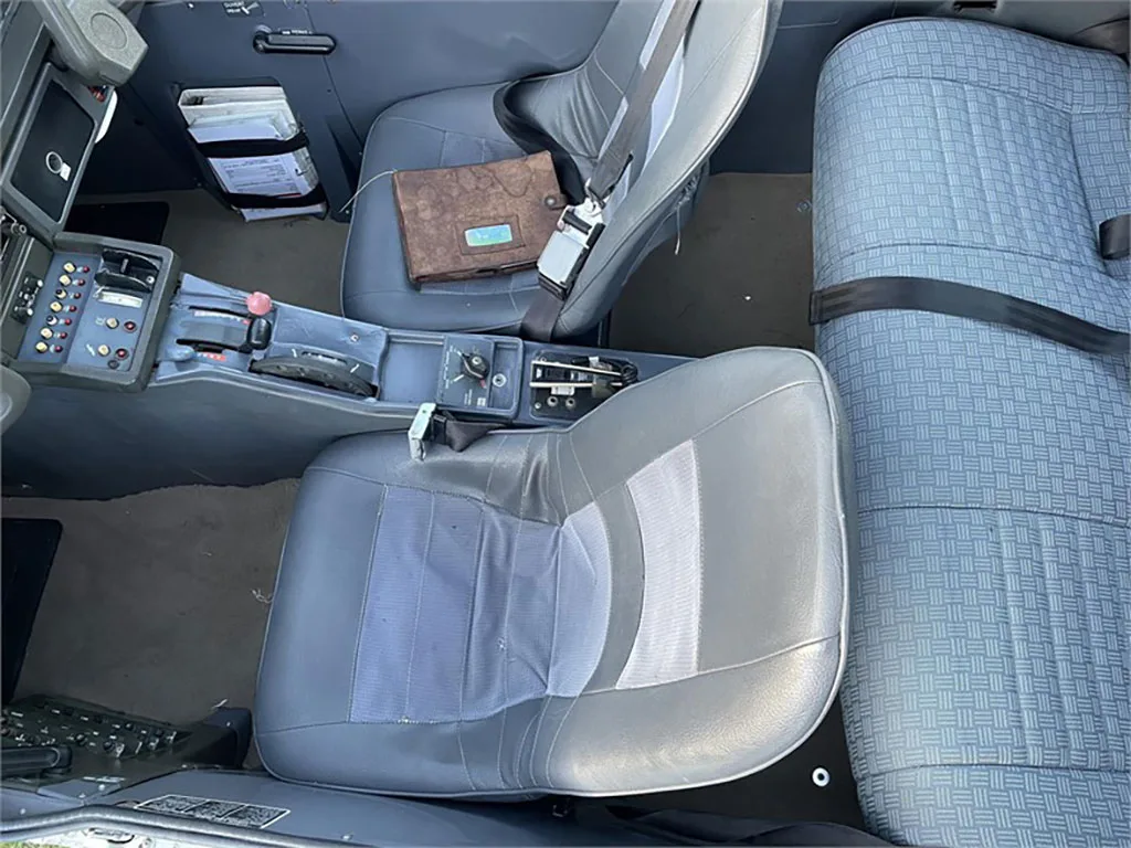 An overhead view of the aircraft's interior, featuring grey pilot seats and a patterned rear bench seat.