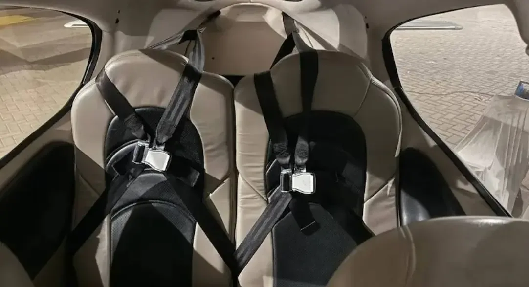 The two rear passenger seats of the aircraft, upholstered in tan and black leather with black seatbelts.