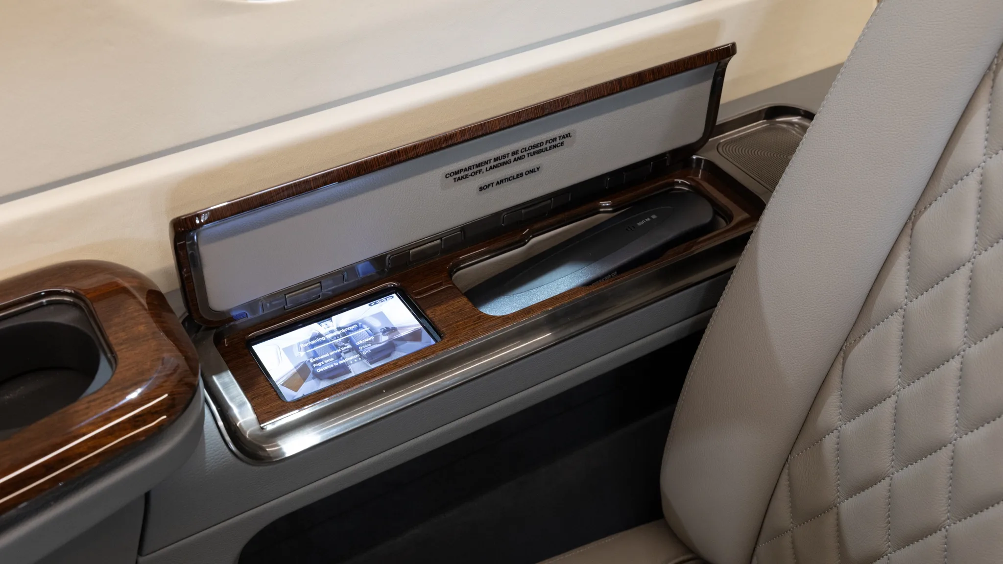 Close-up of the aircraft cabin showing a side table with a phone and monitor.
