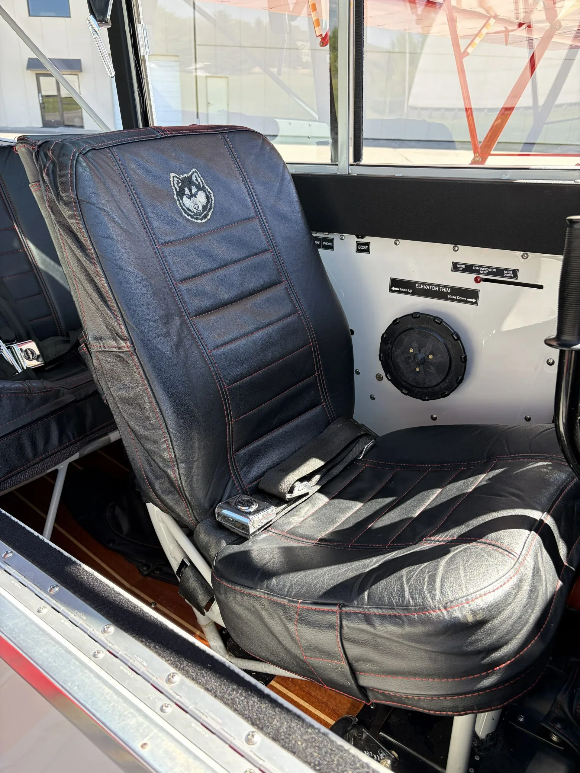 A close-up of the black leather seat with a husky logo on the headrest and red stitching.