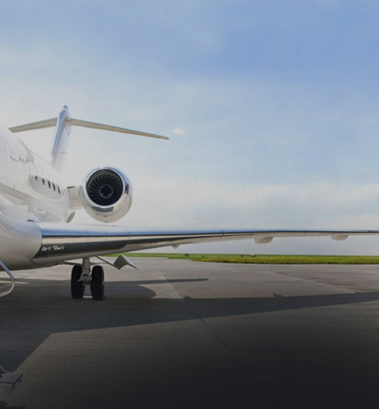 A white private jet parked on a tarmac.