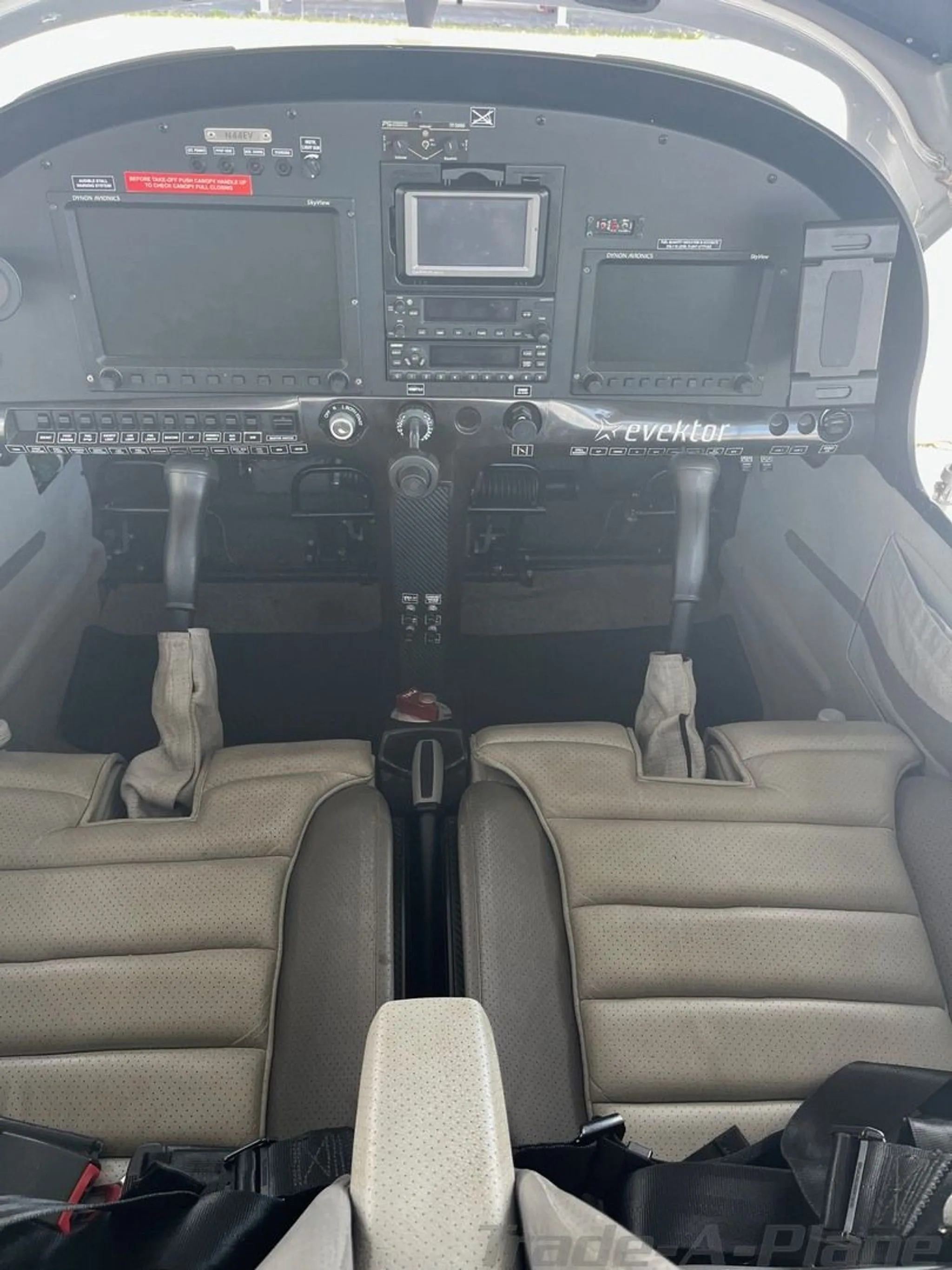 A front-facing view of the cockpit with two large display screens and light gray seats.