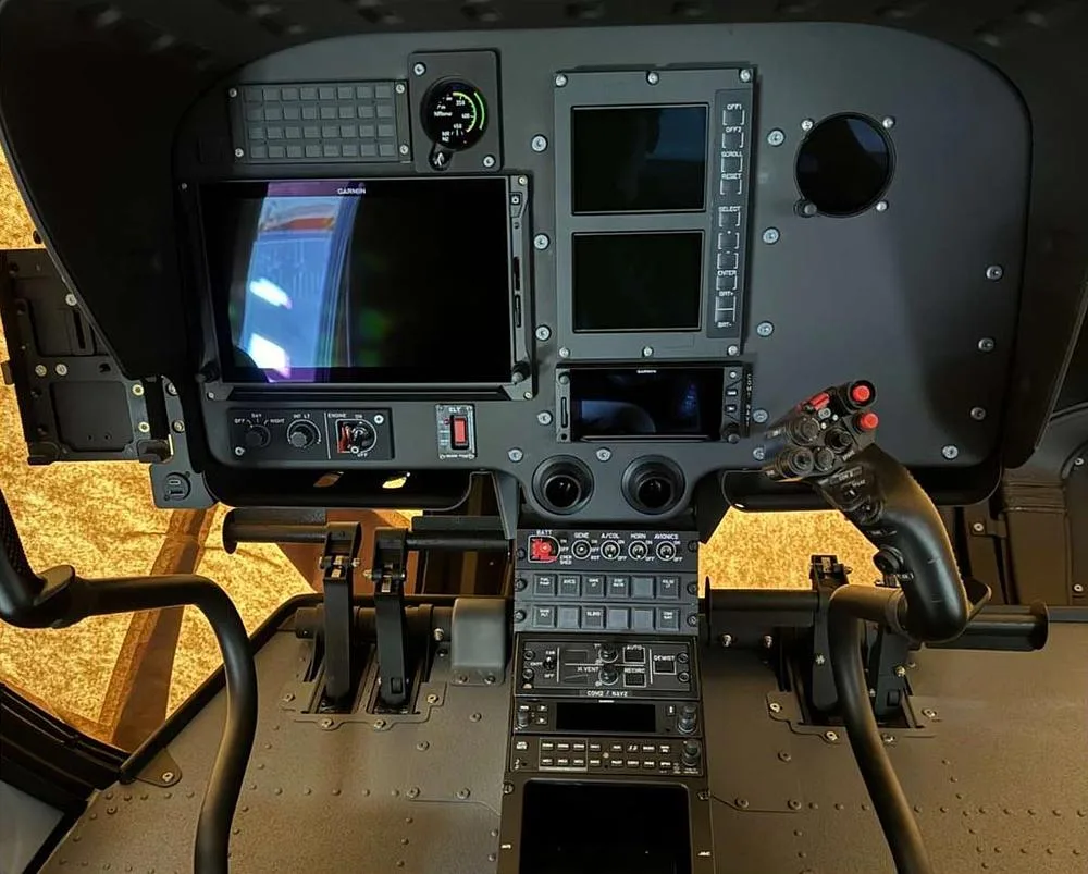 The modern cockpit of a helicopter featuring multiple digital displays and flight controls.