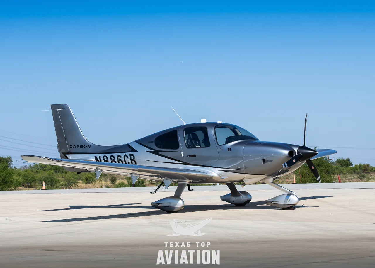 A three-quarter front view of a silver and grey Cirrus SR22 aircraft with registration N886CB on an airfield.