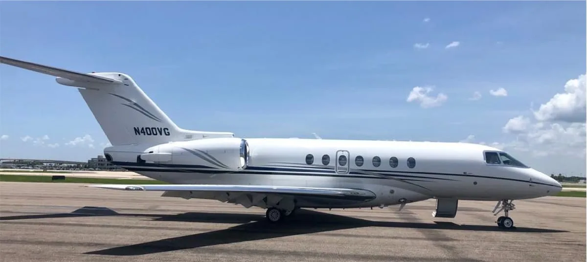 A side view of the N400VG business jet, showing its white fuselage with dark blue and grey stripes on an airport tarmac.