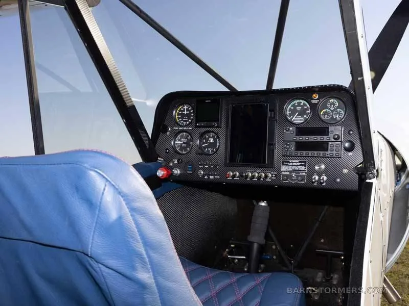 The modern black instrument panel of the Piper Super Cub, featuring digital displays and analog gauges, viewed from the pilot's seat.