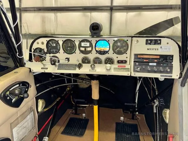 The cockpit of an aircraft featuring a white instrument panel with various analog and digital gauges.