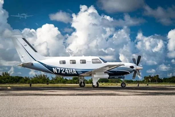 A white and blue Piper M500 (Meridian) aircraft, registration N724HA, parked on a tarmac under a cloudy sky.