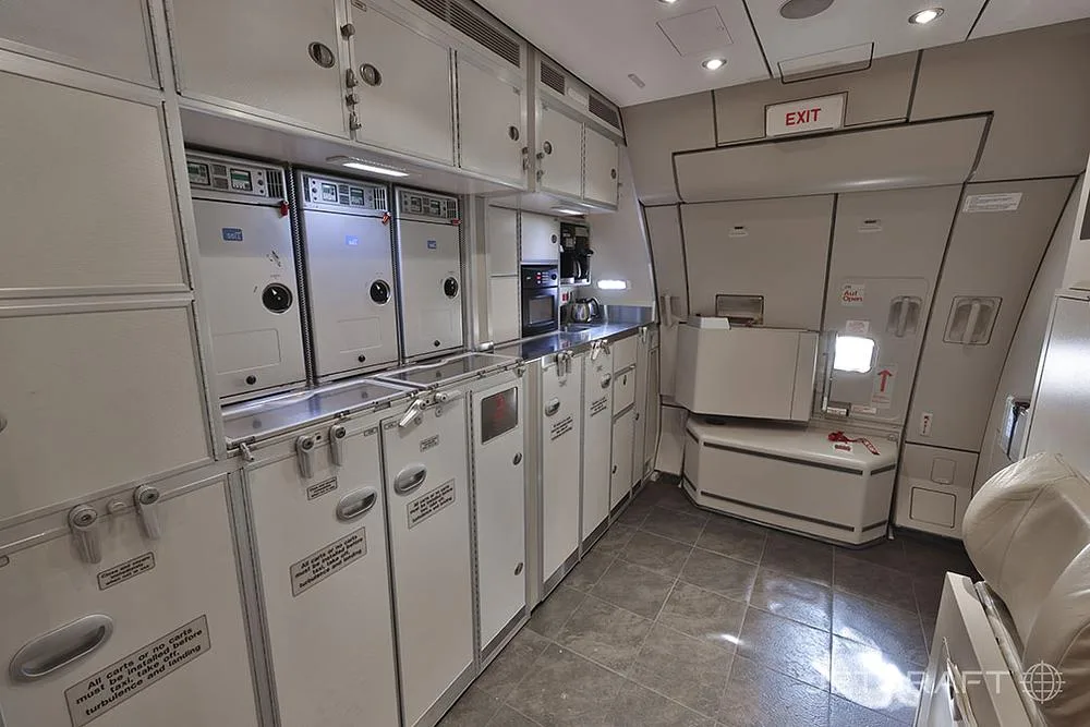 An aircraft galley with multiple ovens, storage compartments, and a coffee maker.
